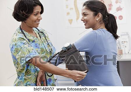 Stock Photo - Nurse taking pregnant woman's blood pressure. Fotosearch