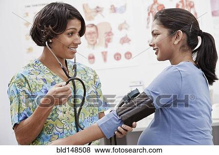 Stock Photo - Nurse taking pregnant woman's blood pressure. Fotosearch