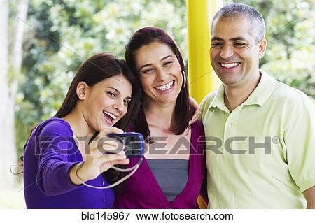 Stock Photo - Parents and daughter taking self-portrait. Fotosearch