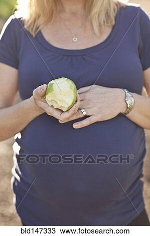 Pregnant Caucasian woman eating apple outdoors View Large Photo Image Stock Image - Pregnant Caucasian woman eating apple outdoors. Fotosearch