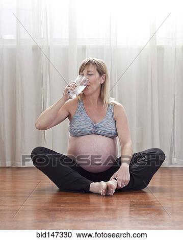 Pregnant Caucasian woman sitting on floor drinking water View Large Photo Image Stock Image - Pregnant Caucasian woman sitting on floor drinking water. Fotosearch