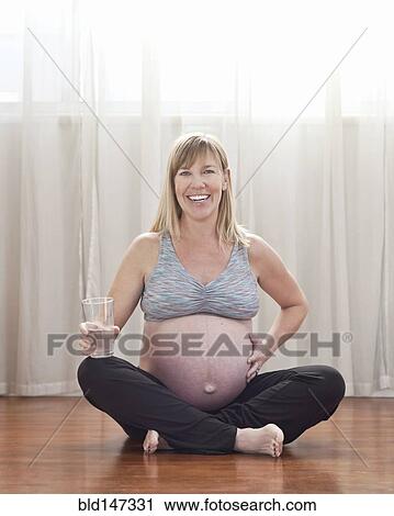 Pregnant Caucasian woman sitting on floor drinking water View Large Photo Image Stock Image - Pregnant Caucasian woman sitting on floor drinking water. Fotosearch