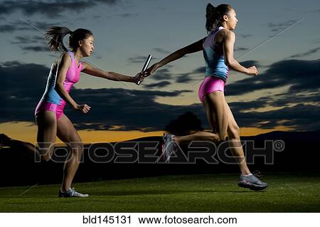 Relay runners passing baton in competition View Large Photo Image Stock Image - Relay runners passing baton in competition. Fotosearch