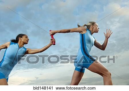 Stock Image - Runners passing baton in relay race. Fotosearch