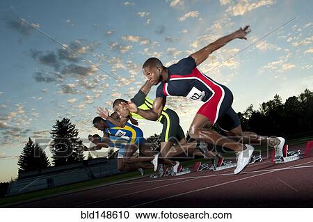 Stock Image - Runners starting on track from starting blocks. Fotosearch