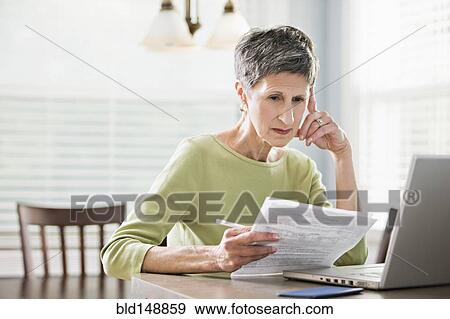 Stock Photo - Senior woman paying bills on laptop. Fotosearch