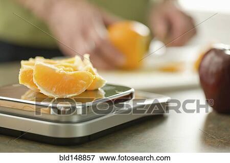 Senior woman weighing orange on scale View Large Photo Image Stock Photo - Senior woman weighing orange on scale. Fotosearch