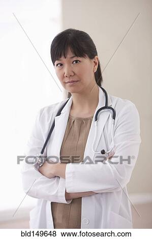 Serious Asian doctor with arms crossed View Large Photo Image Stock Photo - Serious Asian doctor with arms crossed. Fotosearch