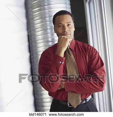Stock Image - Serious businessman with hand on chin. Fotosearch