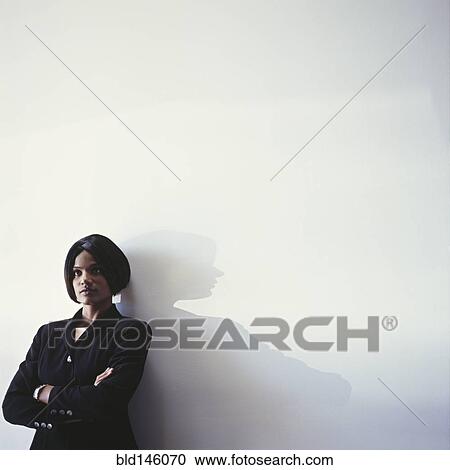 Serious businesswoman leaning against wall View Large Photo Image Stock Image - Serious businesswoman leaning against wall. Fotosearch