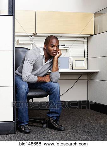 Serious mixed race man sitting in office cubicle View Large Photo Image Stock Photo - Serious mixed race man sitting in office cubicle. Fotosearch