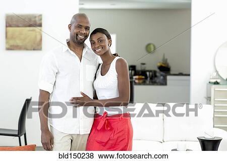 Smiling Black couple standing in living room View Large Photo Image Stock Photo - Smiling Black couple standing in living room. Fotosearch