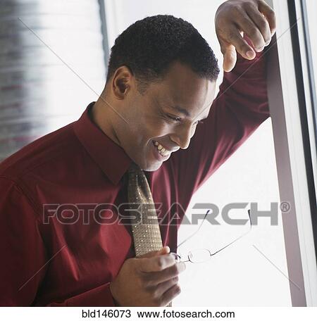 Smiling businessman leaning against wall View Large Photo Image Stock Image - Smiling businessman leaning against wall. Fotosearch