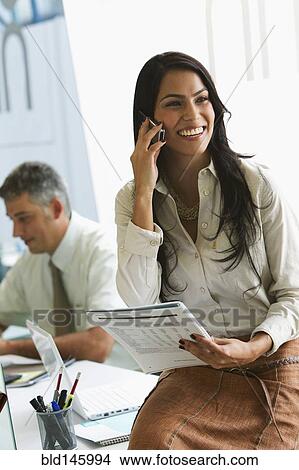 Picture - Smiling businesswoman with paperwork talking on cell phone. Fotosearch