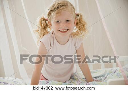 Stock Image - Smiling Caucasian girl in bed. Fotosearch