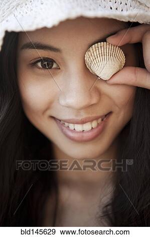Smiling Chinese woman with shell in front of her eye View Large Photo Image Stock Photo - Smiling Chinese woman with shell in front of her eye. Fotosearch