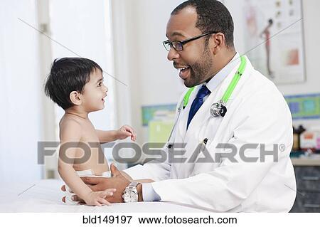 Stock Photo - smiling doctor examining boy in doctor's office. Fotosearch