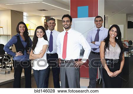 Stock Photo - Smiling Hispanic business people standing together in office. Fotosearch