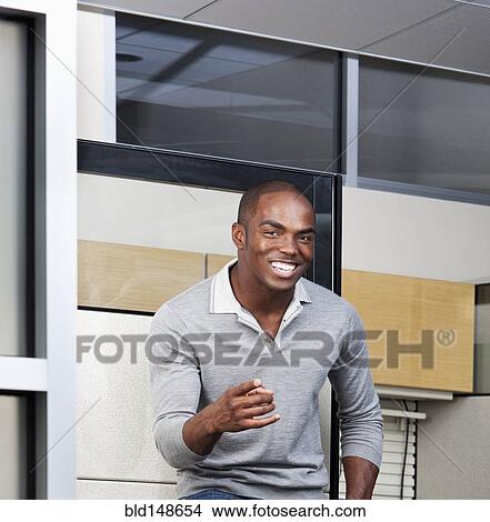 Picture - Smiling mixed race businessman standing in office. Fotosearch