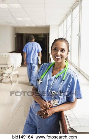 Smiling nurse leaning on window sill in hospital View Large Photo Image Picture - Smiling nurse leaning on window sill in hospital. Fotosearch