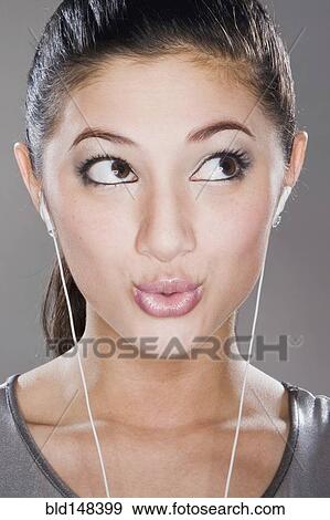 Stock Photo - Surprised mixed race woman listening to headphones. Fotosearch