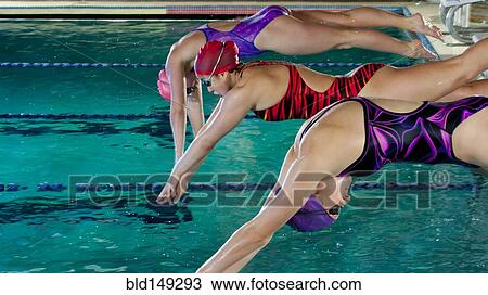 Stock Image - Swimmers diving off starting blocks. Fotosearch