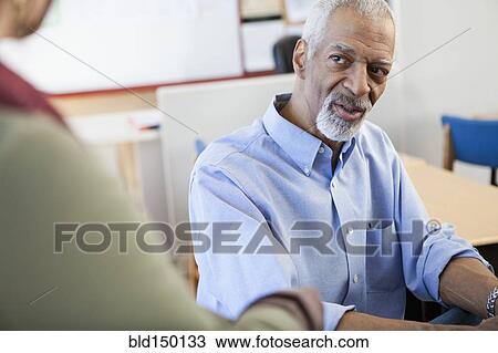 Stock Image - Teacher and student talking in classroom. Fotosearch