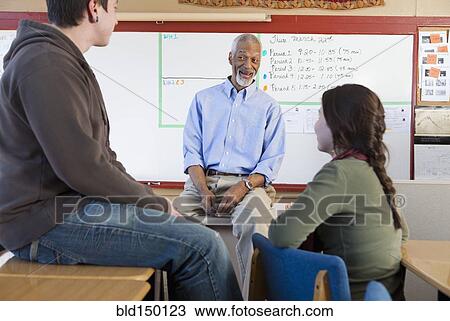 Stock Image - Teacher and students talking in classroom. Fotosearch