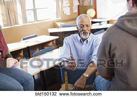 Stock Image - Teacher and students talking in classroom. Fotosearch
