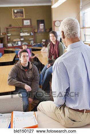 Stock Photo - Teacher and students talking in classroom. Fotosearch