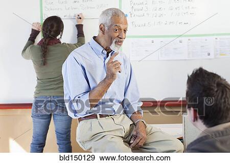 Stock Photo - Teacher and students talking in classroom. Fotosearch