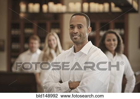 Stock Image - Wait staff standing in restaurant. Fotosearch