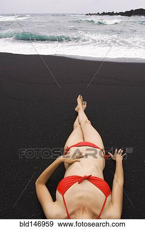 Woman sunbathing on black sand beach View Large Photo Image Stock Photo - Woman sunbathing on black sand beach. Fotosearch