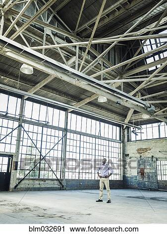 Black businessman standing in empty warehouse View Large Photo Image Stock Image - Black businessman standing in empty warehouse. Fotosearch