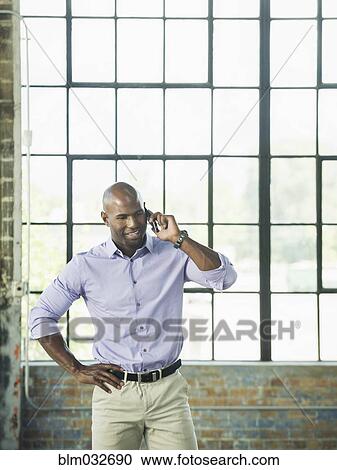 Black businessman talking on cell phone in warehouse View Large Photo Image Stock Image - Black businessman talking on cell phone in warehouse. Fotosearch