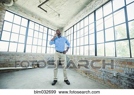 Black businessman talking on cell phone in warehouse View Large Photo Image Stock Photo - Black businessman talking on cell phone in warehouse. Fotosearch