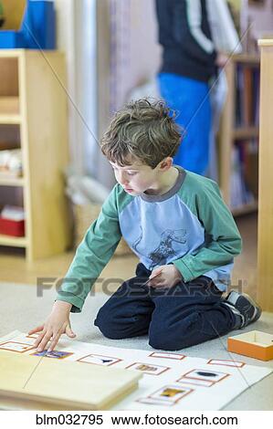 Boy arranging cards on floor in classroom View Large Photo Image Stock Photography - Boy arranging cards on floor in classroom. Fotosearch