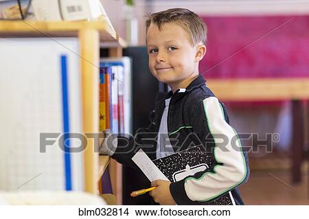 Boy standing near shelf in classroom View Large Photo Image Picture - Boy standing near shelf in classroom. Fotosearch