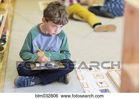 Boy writing in classroom View Large Photo Image Stock Photograph - Boy writing in classroom. Fotosearch
