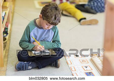 Stock Photography - Boy writing in classroom. Fotosearch