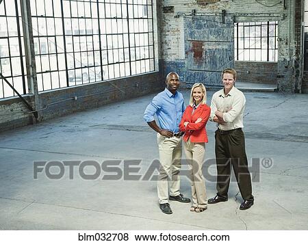 Stock Photo - Business people smiling in empty warehouse. Fotosearch