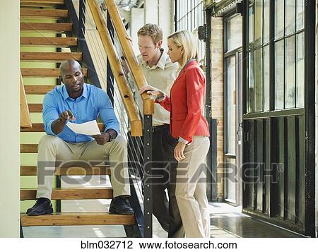 Stock Image - Business people talking on staircase. Fotosearch