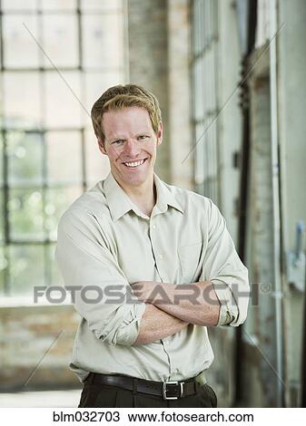 Stock Image - Caucasian businessman smiling in warehouse. Fotosearch