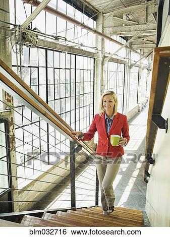 Caucasian businesswoman carrying cup of coffee on warehouse staircase View Large Photo Image Stock Photograph - Caucasian businesswoman carrying cup of coffee on warehouse staircase. Fotosearch
