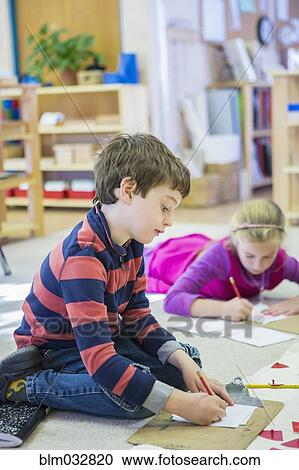Stock Image - Caucasian children writing in classroom. Fotosearch