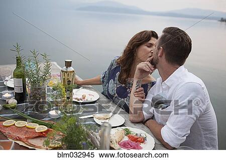 Caucasian couple kissing at table near lake View Large Photo Image Stock Photography - Caucasian couple kissing at table near lake. Fotosearch