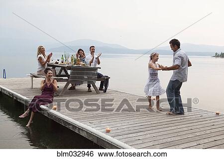 Caucasian family cheering as father and daughter dance on pier over lake View Large Photo Image Stock Photograph - Caucasian family cheering as father and daughter dance on pier over lake. Fotosearch