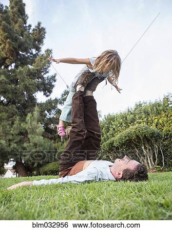 Stock Photograph - Caucasian father and daughter playing in grass. Fotosearch