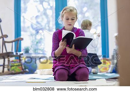 Caucasian girl reading book on floor View Large Photo Image Stock Photo - Caucasian girl reading book on floor. Fotosearch