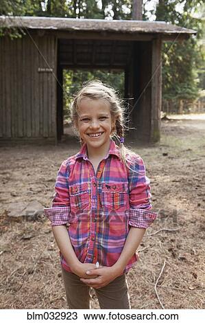 Stock Image - Caucasian girl smiling near barn. Fotosearch